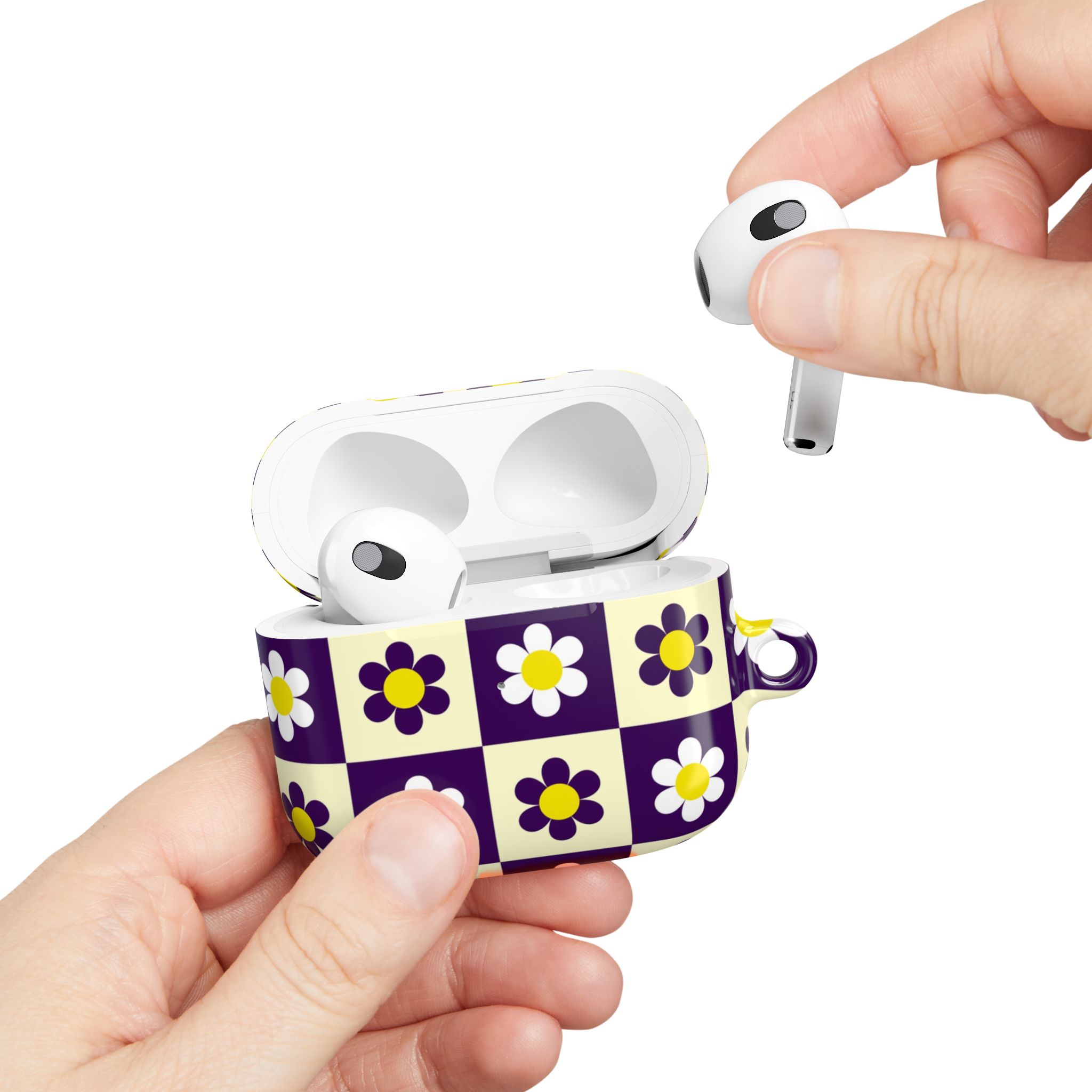 Wireless earbuds in a floral checkered case featuring white and purple flowers with yellow centers. The earbuds are being held above the case with a white background.
